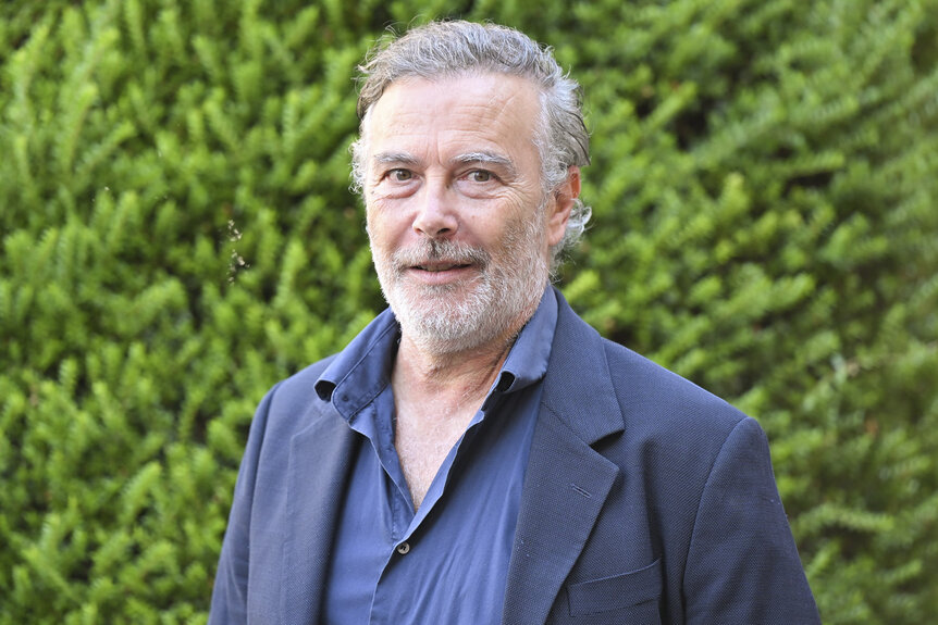 Paolo Sassanelli posing in front of foliage.
