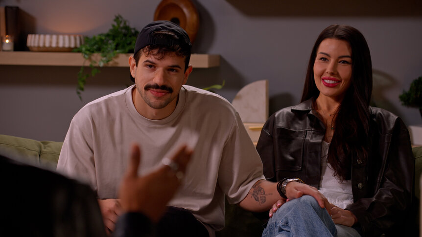 Felipe Cruz and Tori Dahl sitting together on a couch.