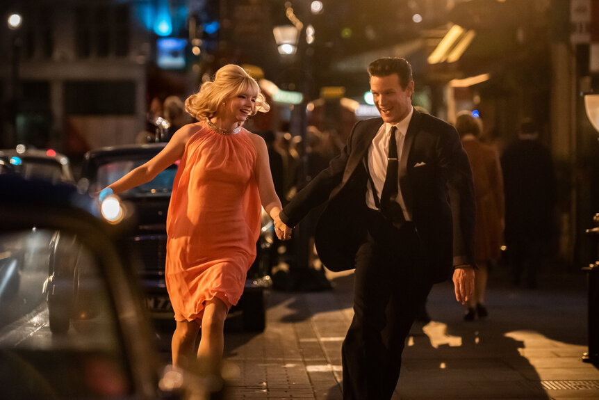 Thomasine McKenzie as Eloise and Matt Smith as Jack runnign together in the streets in the movie Last Night in Soho (2021).